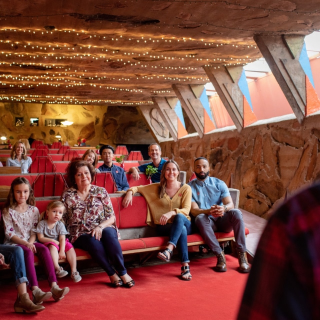 A group of visitors including a family with young children listens to a Museum Educator during a Family Tour of Taliesin West.