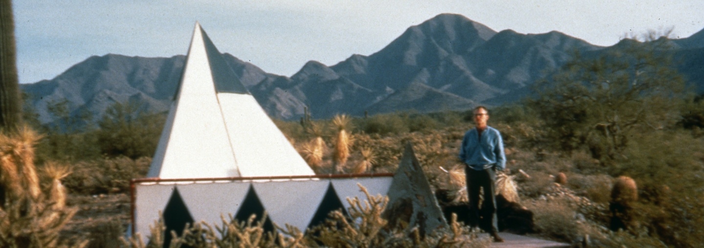 David Dodge in the Sonoran desert standing next to his the triangular tent.